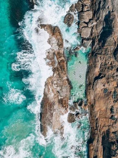 Foto de detalhe das águas cristalinas batendo nas pedras que formam as piscinas naturais do Abricó